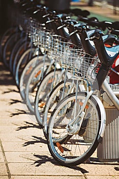 Row of parked vintage bicycles bikes for rent on sidewalk.