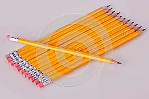 A row of pencils enter top left at an angle with erasers flush