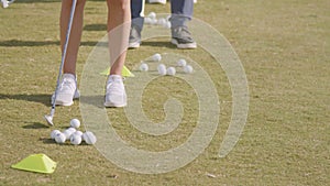 Row of people training for the best golf swing. Practicing outdoor. Feet close up