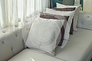 Row of pillow setting up on beige sofa