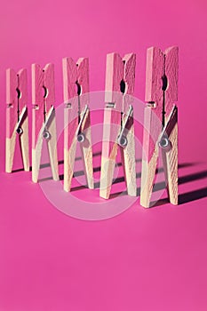 Row of pink painted clothes pegs on pink background