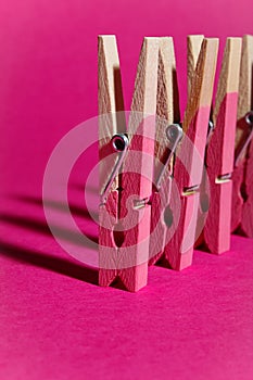 Row of pink painted wooden pegs on pink background