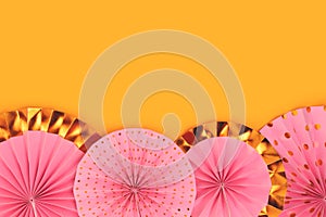 Row of pink paper fans on a yellow background.