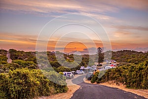 Row of pitched tents and cars at Australian camping grounds at sunset.