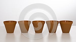 Row of plastic flower pots on white background with reflection.