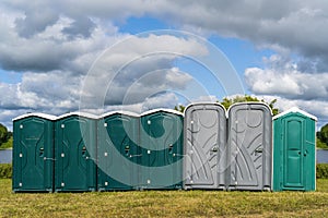 Row of plastic portable toilets at an outdoor event