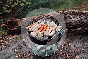 Row of pork and beef bratwurst grilling over a barbecue fire on the summer vacation