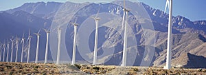 Row of power generating windmills in front of mountain range