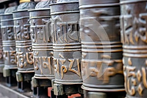 Row of prayer bells and some spinning in a buddhist temple, in kathmandu nepal