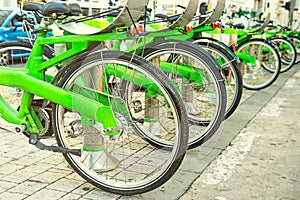 Row of public bicycle on rental station on city background. Eco-friendly and convenient transportation in the city. Close up, sele