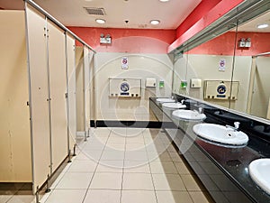 Row of public restrooms and white ceramic wash basins