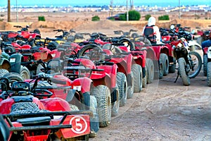 A row of red all-terrain vehicles ready for a new adventure in the desert dunes