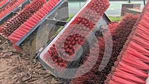 A row of red football boot mud scraper brushes