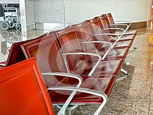A row of red leather chairs are empty in a waiting room