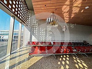 A row of red leather chairs are empty in a waiting room