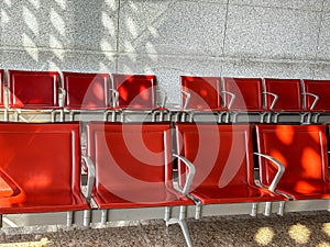 A row of red leather chairs are empty in a waiting room