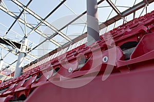 A row of red plastic chairs on a stadium