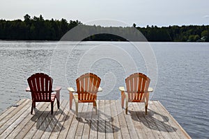 Row of red and yellow Muskoka chairs casting shadows on dock at Spring Lake