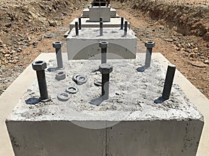 Row of reinforced concrete foundations with metal anchor bolts designed for the installation of metal columns