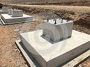 Row of reinforced concrete foundations with metal anchor bolts for the installation of metal columns