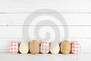 Row of rustic farmhouse style cloth Easter Eggs against a white wood background