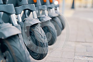 Row of scooters with rubber tires parked on sidewalk