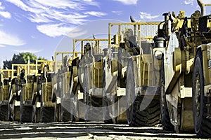 Row of scrapers and heavy equipment lined-up at a land development in Rocky View County Alberta Canada.