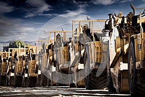 Row of scrapers parked on land being developed for mixed industrial and commercial businesses.