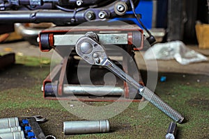 Row of screws and wrench tools on a floor in workshop near repaired old bike or motorcycle engine. Industrial scene with
