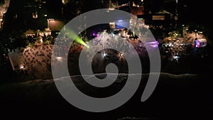 Row of seaside beach nightclubs aerial view from water. Sea front cafes and restaurants colourful lights at night, crowd