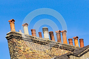 Row of several different style chimneys above roof tops