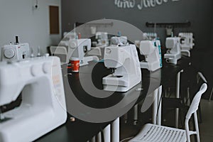 White sewing machines on the table. A row of sewing machines, a workshop for tailors photo