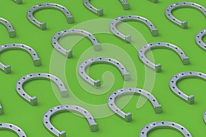 Row of silver horseshoes on a green background. Symbol of luck
