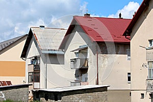 Row of similar suburban family houses with old dilapidated facade and renovated roof next to building blocks outdoor storage sheds