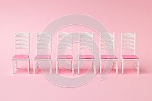 A row of six chairs on a pink background