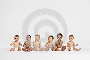 Row of six multi ethnic Babies smiling in studio