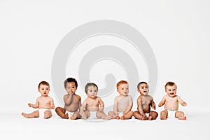 Row of six multi ethnic Babies smiling in studio