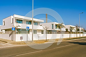 Row of sleek, modern condos lines the street, blue sky in the background