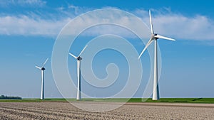 A row of sleek wind turbines stands tall in a vast field in Flevoland, the Netherlands, harnessing the power of the wind