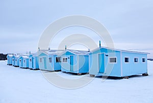 Row of small pale blue huts for ice fishing seen during an early winter morning in Sainte-Anne-de-la-PÃ©rade