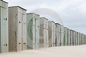 Row of small wooden buildings on beach near the coast. Seaside shed leisure background. Perspective to the right.