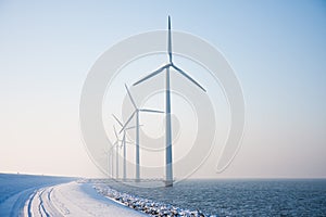 Row of snowy windmills standing in Dutch sea