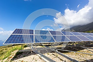 Row of solar collectors on mountain with blue sky