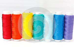 A row of spools of thread. rainbow colors