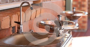 A row of stainless steel communal water fountains or stations