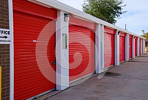 Row of storage garage units with red doors