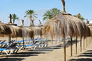 Row of straw umbrellas on the beach in Marbella, Spain photo