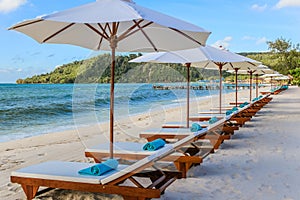 A row of sunbeds and towels at a beach resort.