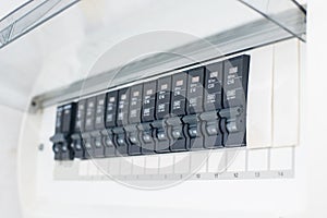 A row of switched off household electrical circuit breakers on a wall panel