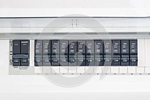 A row of switched off household electrical circuit breakers on a wall panel